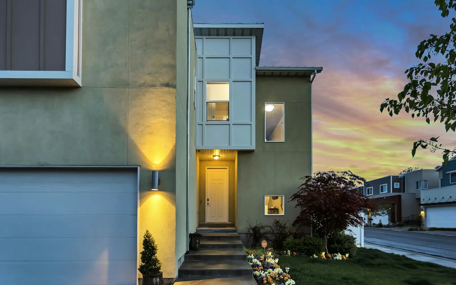 A two-story home at dusk with its porch light on